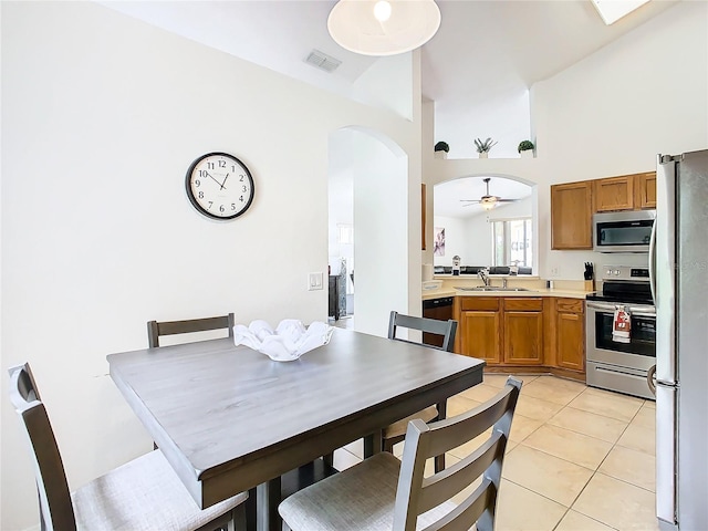 tiled dining room featuring ceiling fan, high vaulted ceiling, and sink