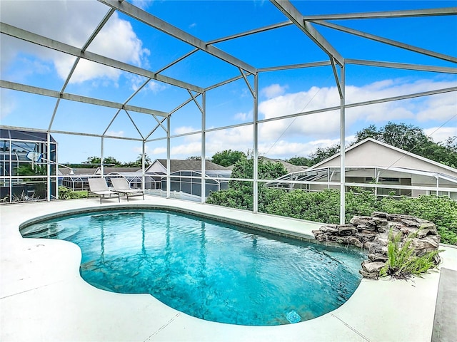 view of pool with glass enclosure and a patio