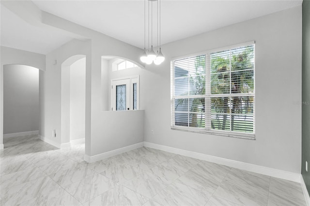 empty room with a wealth of natural light and a chandelier