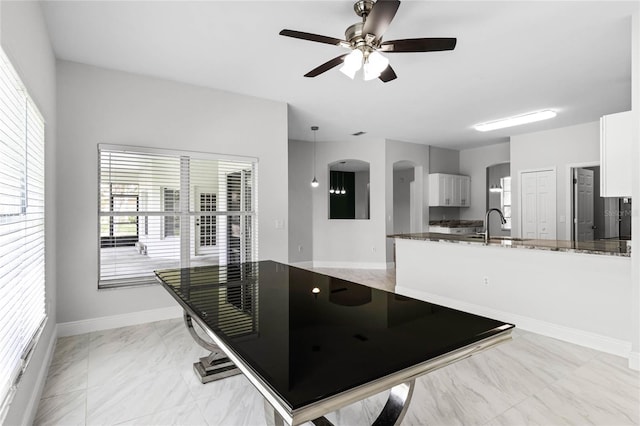 kitchen with white cabinets, ceiling fan, dark stone countertops, and kitchen peninsula