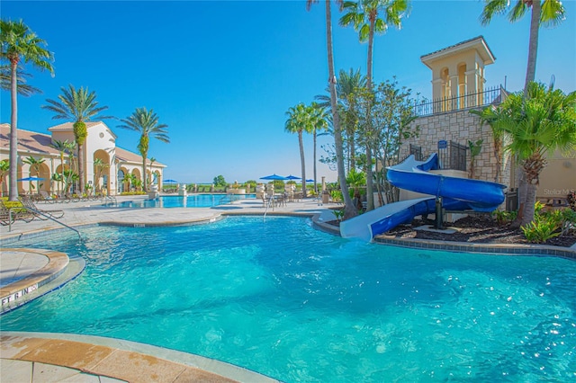 view of swimming pool with a water slide and a patio area