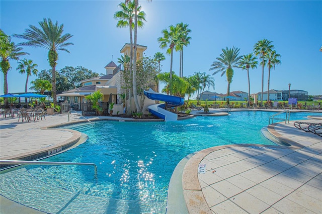 view of swimming pool with a water slide and a patio