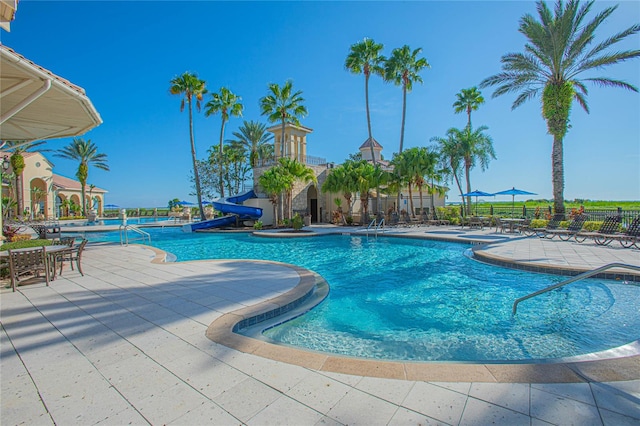 view of swimming pool with a water slide and a patio