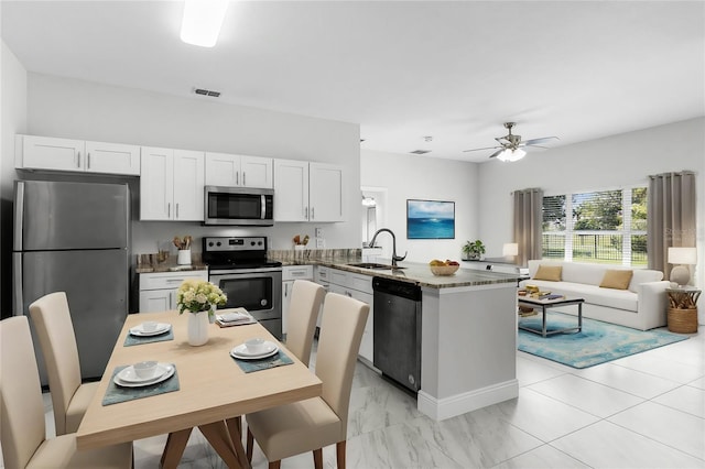 kitchen with appliances with stainless steel finishes, white cabinetry, sink, kitchen peninsula, and ceiling fan