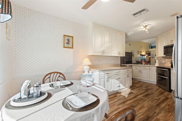 kitchen with light countertops, range with two ovens, visible vents, and wallpapered walls