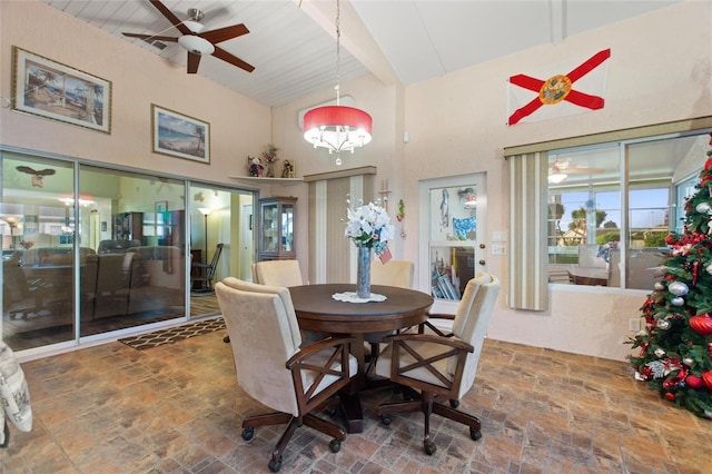 dining room with a ceiling fan, stone finish flooring, and high vaulted ceiling