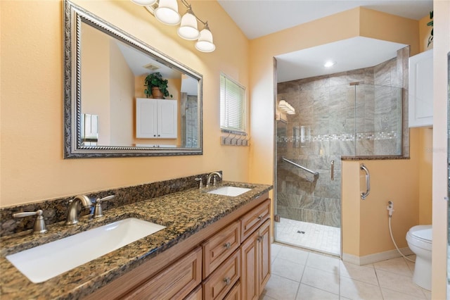 bathroom featuring toilet, a shower stall, double vanity, and a sink