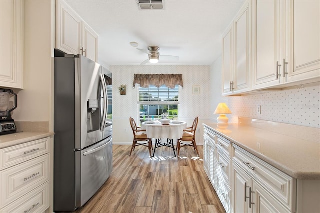 kitchen featuring white cabinetry, visible vents, light countertops, stainless steel fridge with ice dispenser, and wallpapered walls