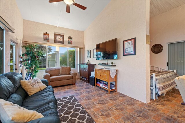 living room featuring high vaulted ceiling, a ceiling fan, and a textured wall