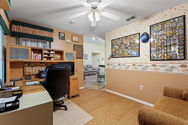 office area with a textured ceiling, ceiling fan, light wood-style flooring, visible vents, and baseboards