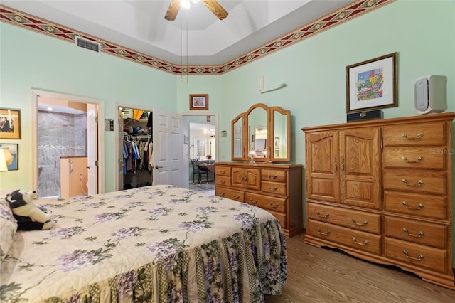 bedroom with ensuite bathroom, wood finished floors, visible vents, a spacious closet, and a closet