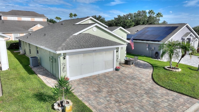 view of front facade with central AC unit, an attached garage, decorative driveway, stucco siding, and a front lawn