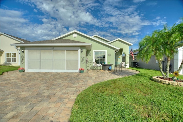 ranch-style house with decorative driveway, stucco siding, a front yard, a patio area, and a garage