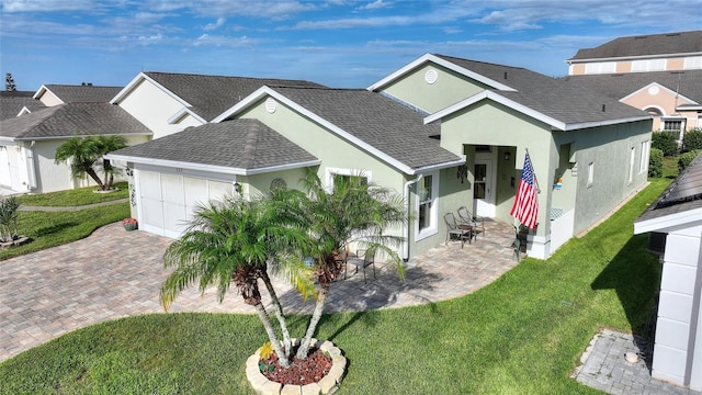 view of front of house featuring a garage, a shingled roof, decorative driveway, stucco siding, and a patio area