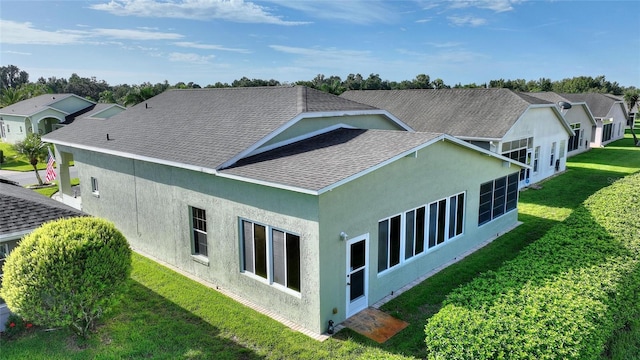 exterior space with stucco siding, a residential view, a lawn, and roof with shingles