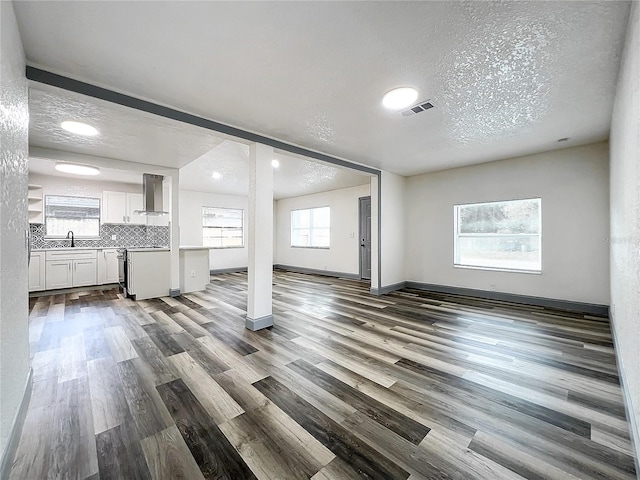 unfurnished living room featuring a textured ceiling, sink, and wood-type flooring