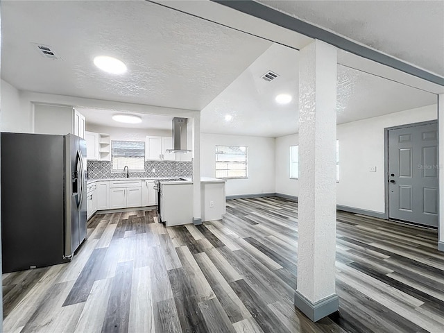 kitchen featuring open shelves, white cabinets, light countertops, stainless steel fridge with ice dispenser, and wall chimney exhaust hood