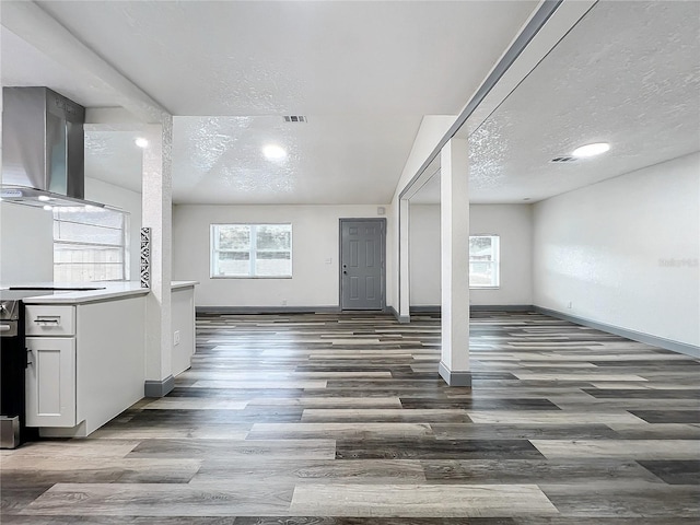 unfurnished living room with a textured ceiling, dark wood-style floors, and a healthy amount of sunlight