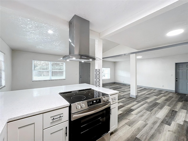 kitchen featuring island exhaust hood, light wood-style floors, white cabinets, a textured ceiling, and stainless steel electric range