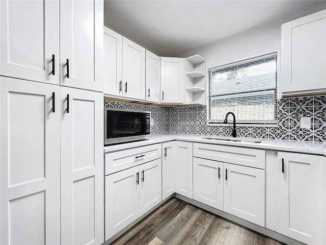 kitchen with open shelves, stainless steel microwave, a sink, and white cabinets