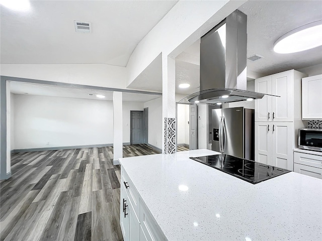 kitchen with island exhaust hood, stainless steel appliances, visible vents, white cabinetry, and light stone countertops