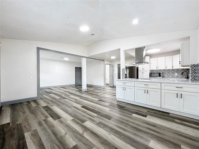 kitchen featuring white cabinets, vaulted ceiling, light countertops, appliances with stainless steel finishes, and island exhaust hood