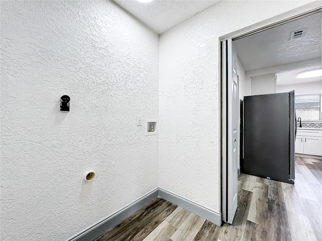 clothes washing area featuring hookup for a washing machine, visible vents, a textured wall, wood finished floors, and laundry area