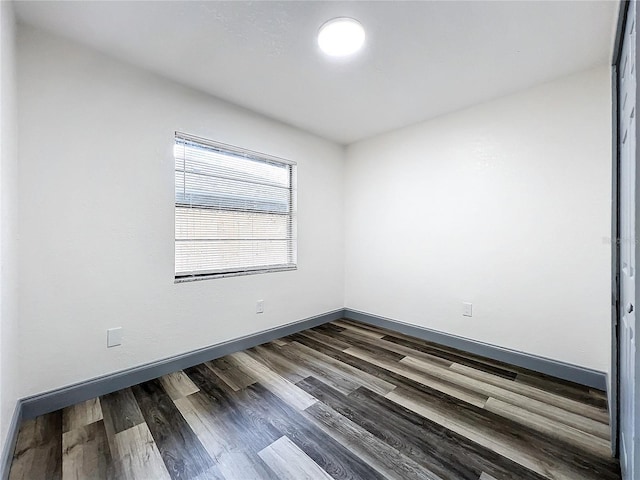 spare room featuring dark wood-style floors and baseboards