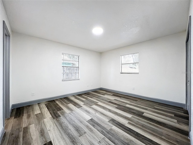 empty room with a wealth of natural light, baseboards, and wood finished floors