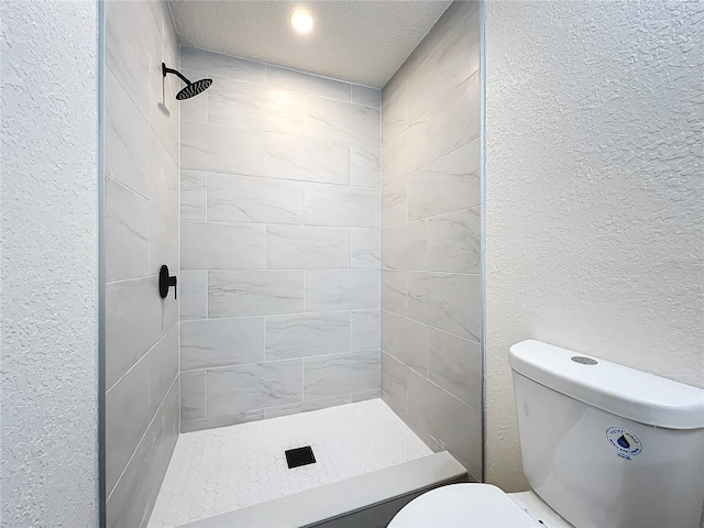 full bathroom featuring toilet, a shower stall, a textured ceiling, and a textured wall