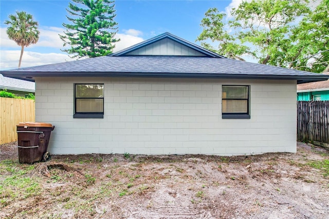 view of property exterior featuring roof with shingles and fence