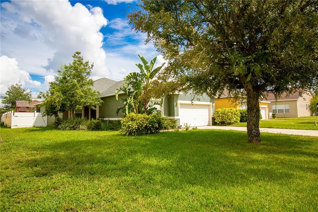 view of property hidden behind natural elements with a front lawn and a garage