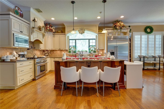 kitchen with light wood-type flooring, a center island, decorative backsplash, and built in appliances