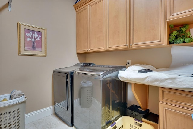 laundry area featuring baseboards, light tile patterned flooring, cabinet space, and washer and dryer