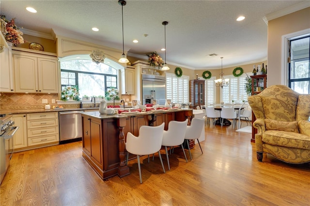 kitchen featuring stainless steel appliances, a breakfast bar area, light wood-style flooring, and a healthy amount of sunlight