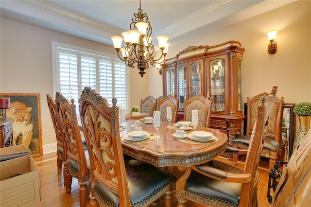 dining area featuring a notable chandelier, crown molding, baseboards, and wood finished floors