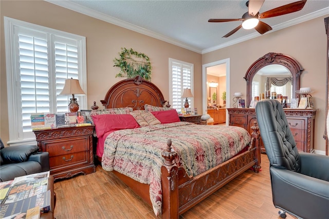 bedroom featuring ornamental molding, light wood-type flooring, and a ceiling fan