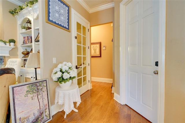 hall featuring light wood-type flooring, visible vents, crown molding, and baseboards