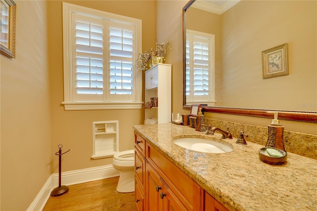 bathroom with crown molding, toilet, vanity, wood finished floors, and baseboards