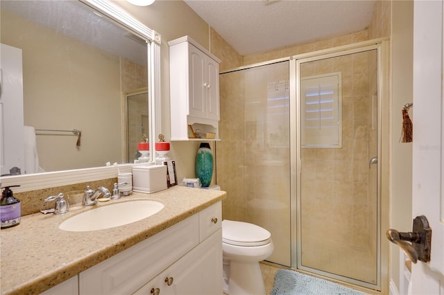 bathroom with toilet, a shower stall, a textured ceiling, and vanity