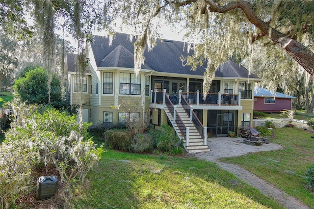 view of front of house featuring a deck, a sunroom, stairway, and a front lawn