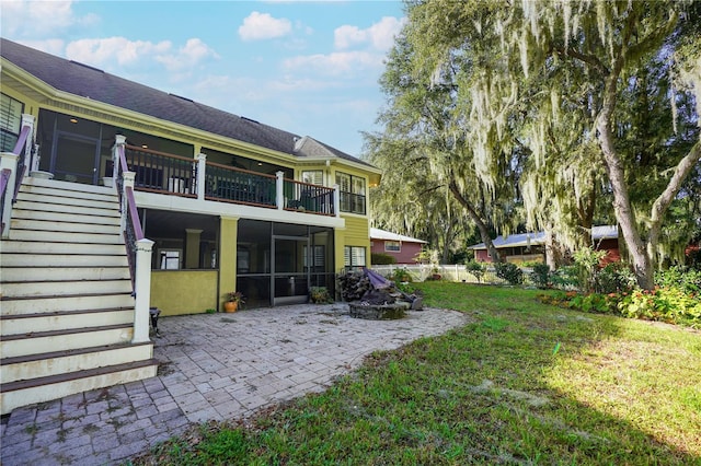 back of property with a yard, stairway, a patio area, and a sunroom