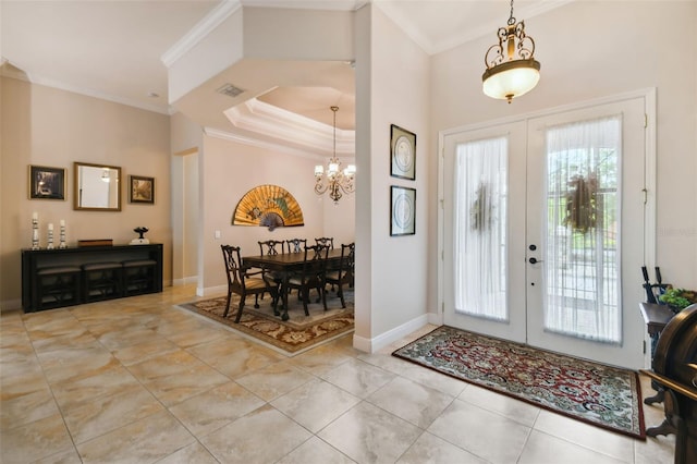 tiled foyer entrance with a notable chandelier, a raised ceiling, french doors, and crown molding