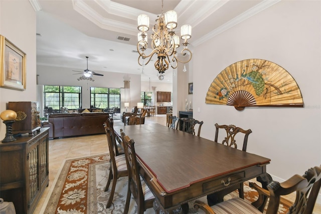 tiled dining room with ceiling fan with notable chandelier, ornamental molding, and a tray ceiling