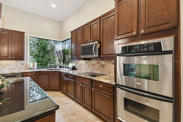 kitchen with appliances with stainless steel finishes, backsplash, sink, light stone counters, and light tile patterned floors