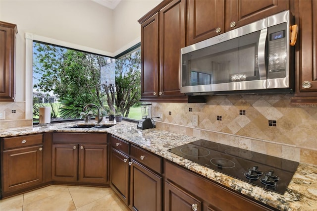 kitchen with sink, backsplash, a healthy amount of sunlight, and light stone countertops