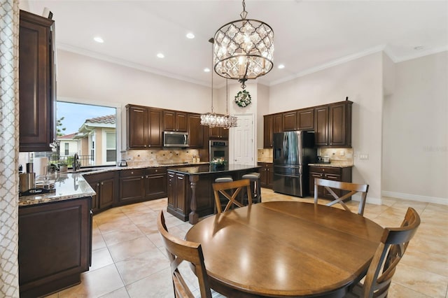 kitchen with appliances with stainless steel finishes, a chandelier, dark brown cabinetry, tasteful backsplash, and a kitchen island