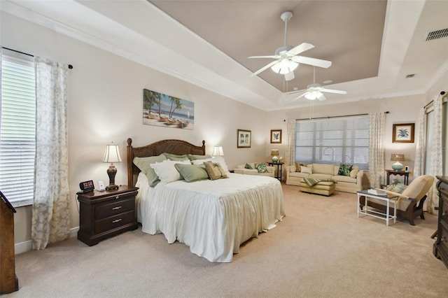 carpeted bedroom with ceiling fan, crown molding, and a tray ceiling