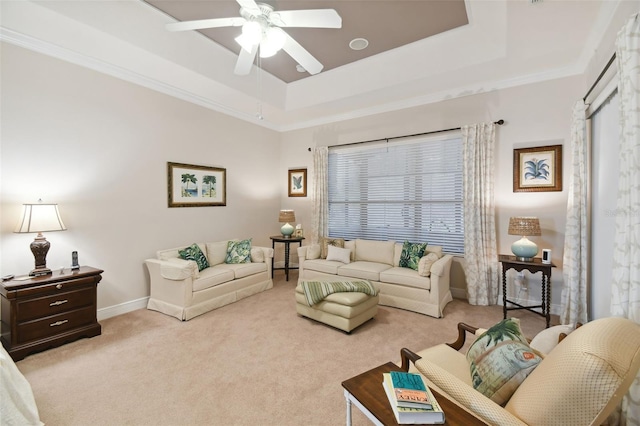 living room featuring ceiling fan, ornamental molding, a raised ceiling, and light colored carpet