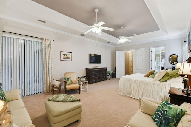 bedroom with ornamental molding, light colored carpet, a tray ceiling, ceiling fan, and ensuite bathroom